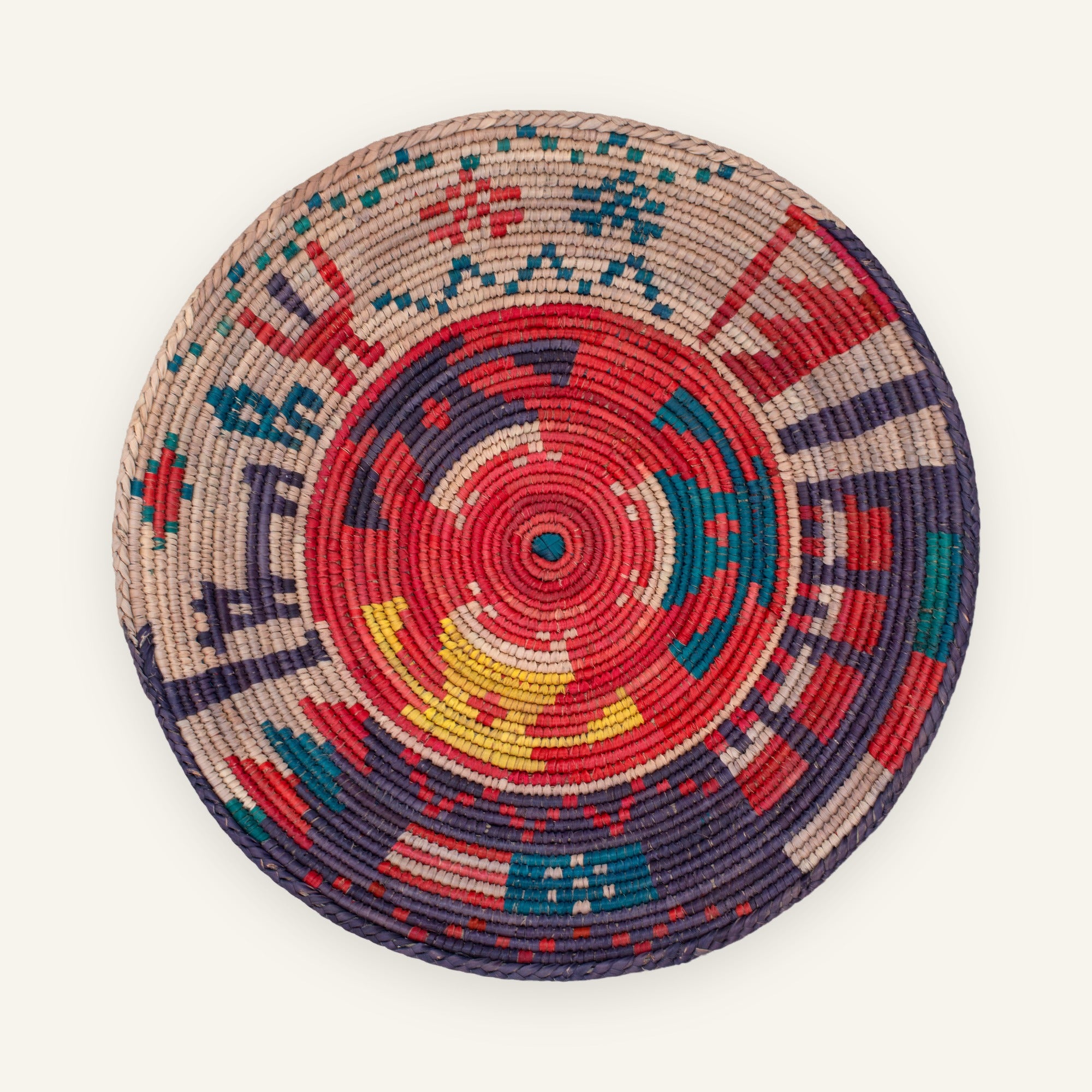 Ancient Lore Morganite handmade woven wicker wall basket with a red radial center, purple, teal blue, beige, and yellow geometric bands.