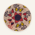 Buttefly Brazen woven wicker wall basket with a black spiral center, red geometric forms, yellow accents, and a natural beige ground