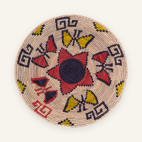 Buttefly Brazen woven wicker wall basket with a black spiral center, red geometric forms, yellow accents, and a natural beige ground