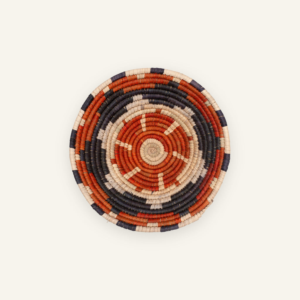 Cinder woven wicker wall basket with concentric orange, black, and beige rings