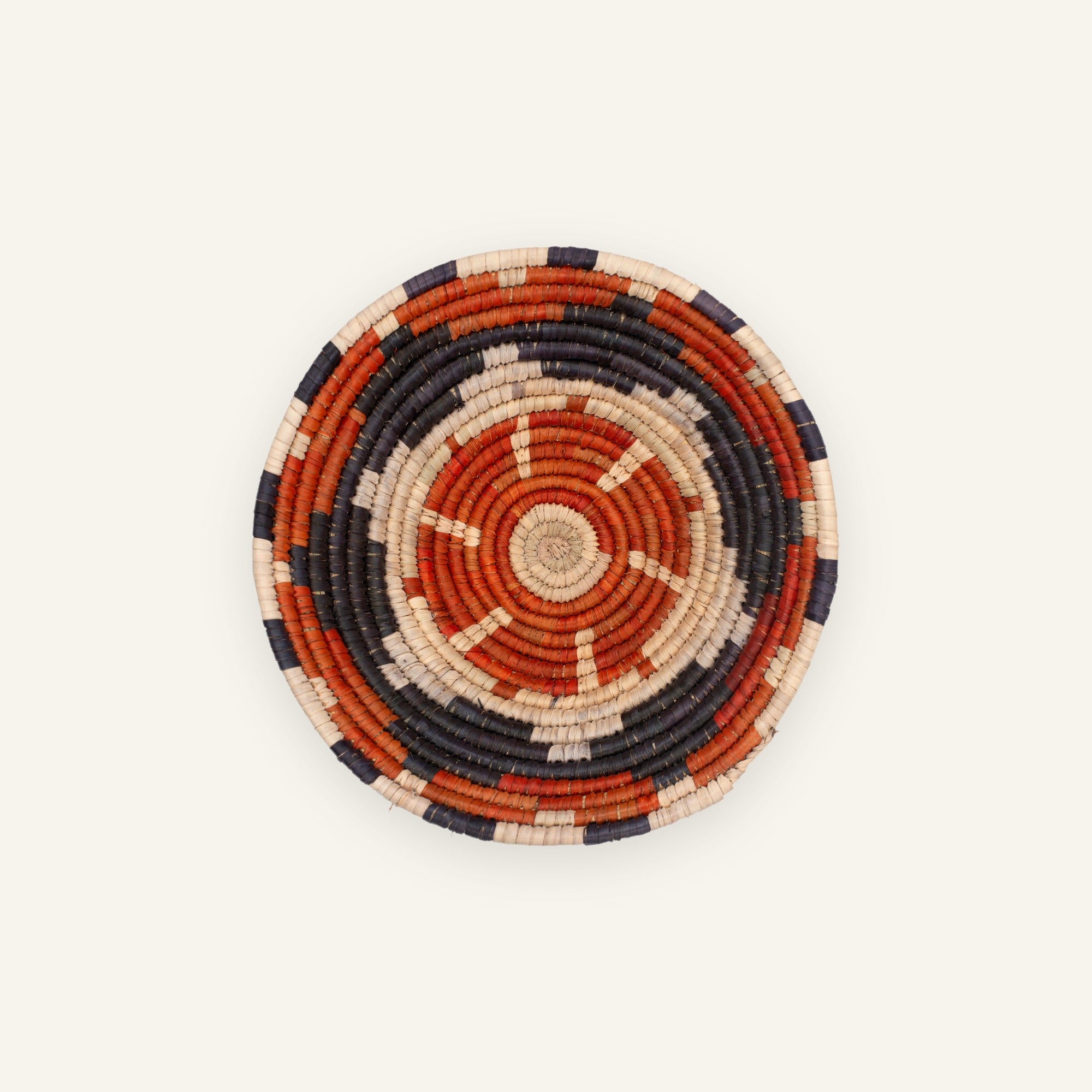 Cinder woven wicker wall basket with concentric orange, black, and beige rings