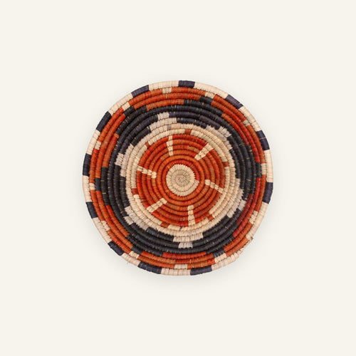 Cinder woven wicker wall basket with concentric orange, black, and beige rings