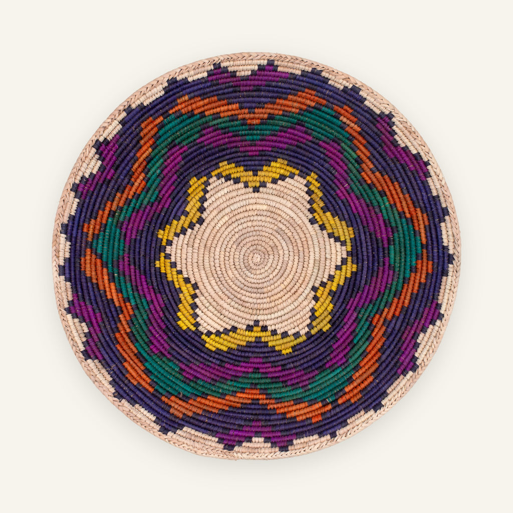 Colorblast woven wicker wall basket with a beige spiral center and geometric rings in purple, green, orange, and yellow.
