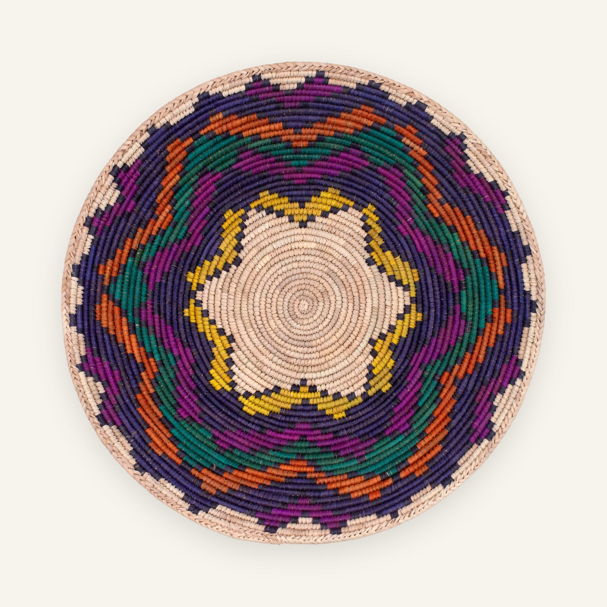 Colorblast woven wicker wall basket with a beige spiral center and geometric rings in purple, green, orange, and yellow.