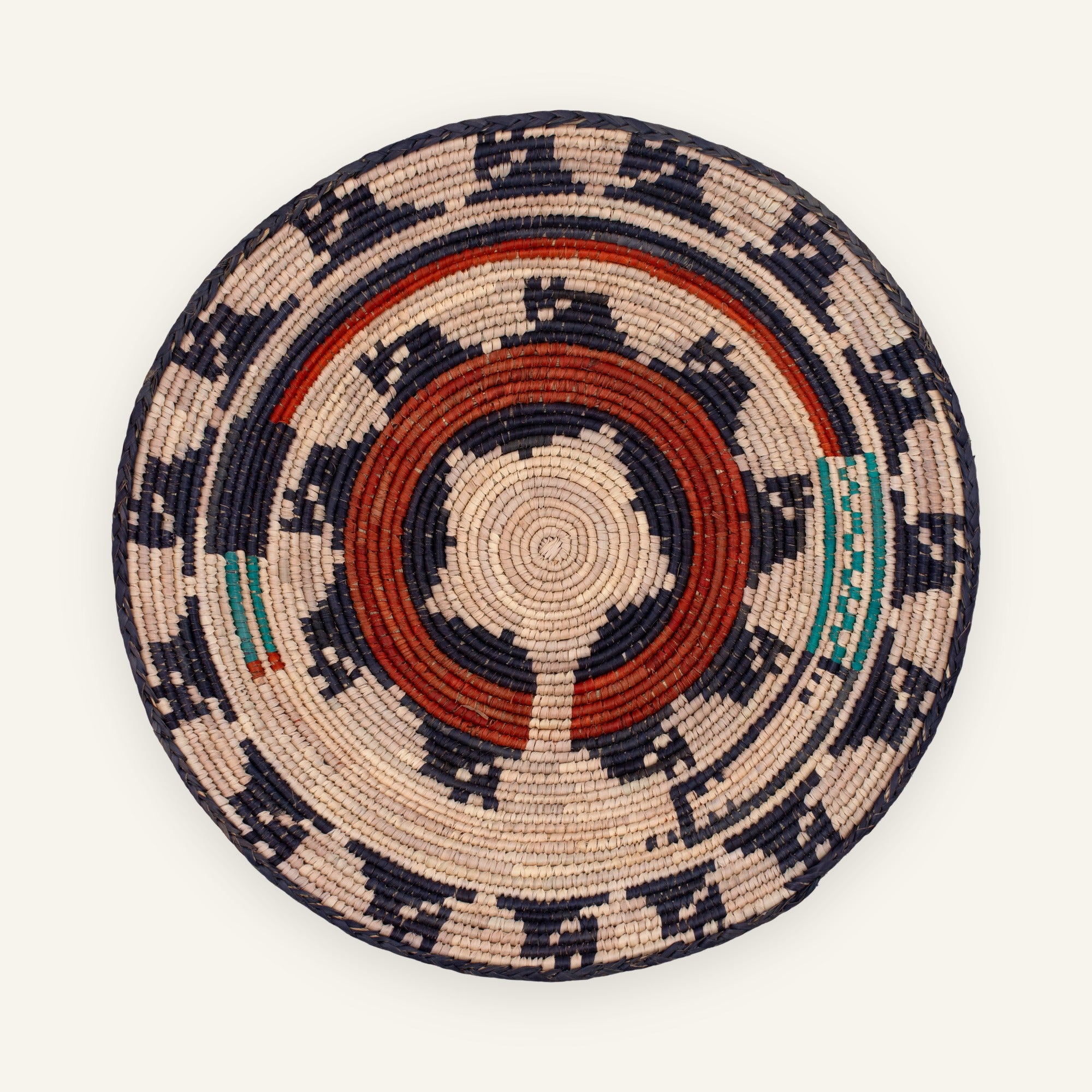 Dark Waves handmade woven wicker wall basket with concentric geometric rings in beige, navy, red, and green.