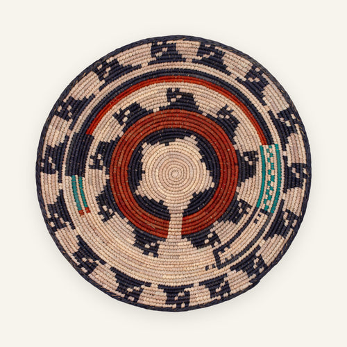 Dark Waves handmade woven wicker wall basket with concentric geometric rings in beige, navy, red, and green.