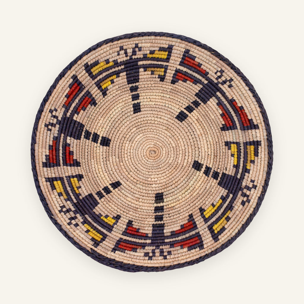 Dragonfly Jasper woven wicker wall basket with a natural beige ground, dark braided border, and red and yellow geometric arc pattern.