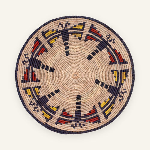 Dragonfly Jasper woven wicker wall basket with a natural beige ground, dark braided border, and red and yellow geometric arc pattern.