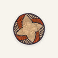 Ember Passage handmade woven wicker wall basket with a beige coiled center, orange curved bands, and dark geometric border.