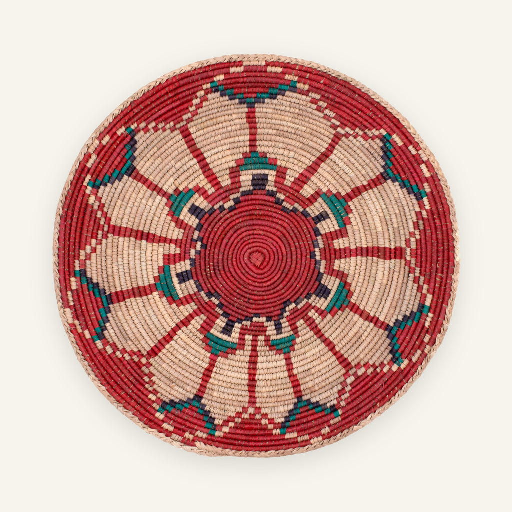 Fluorescence Blush handmade woven wicker wall basket with a red spiral center, beige radial panels, and teal-blue geometric accents.