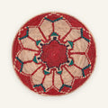 Fluorescence Blush handmade woven wicker wall basket with a red spiral center, beige radial panels, and teal-blue geometric accents.