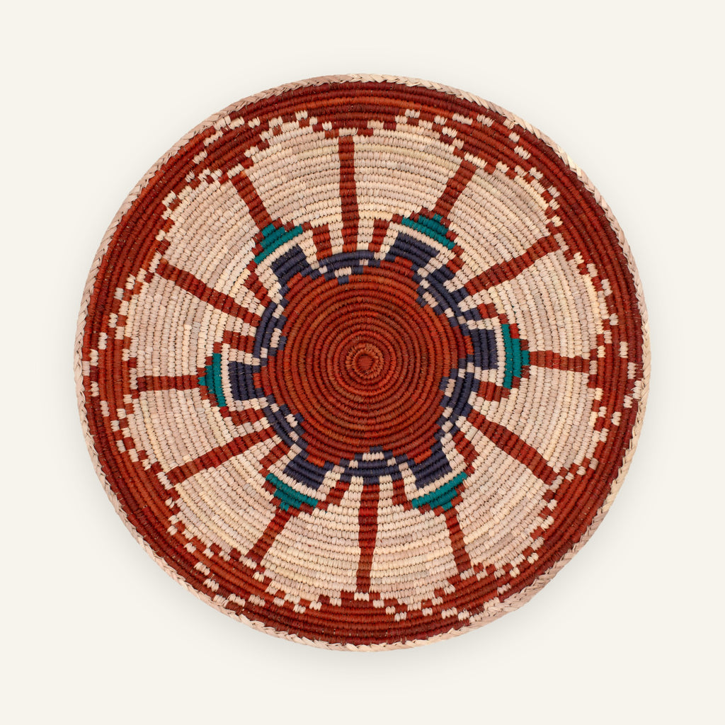 Fluorescence Subtle woven wicker wall basket with red, cream, deep blue, and teal geometric sunburst pattern