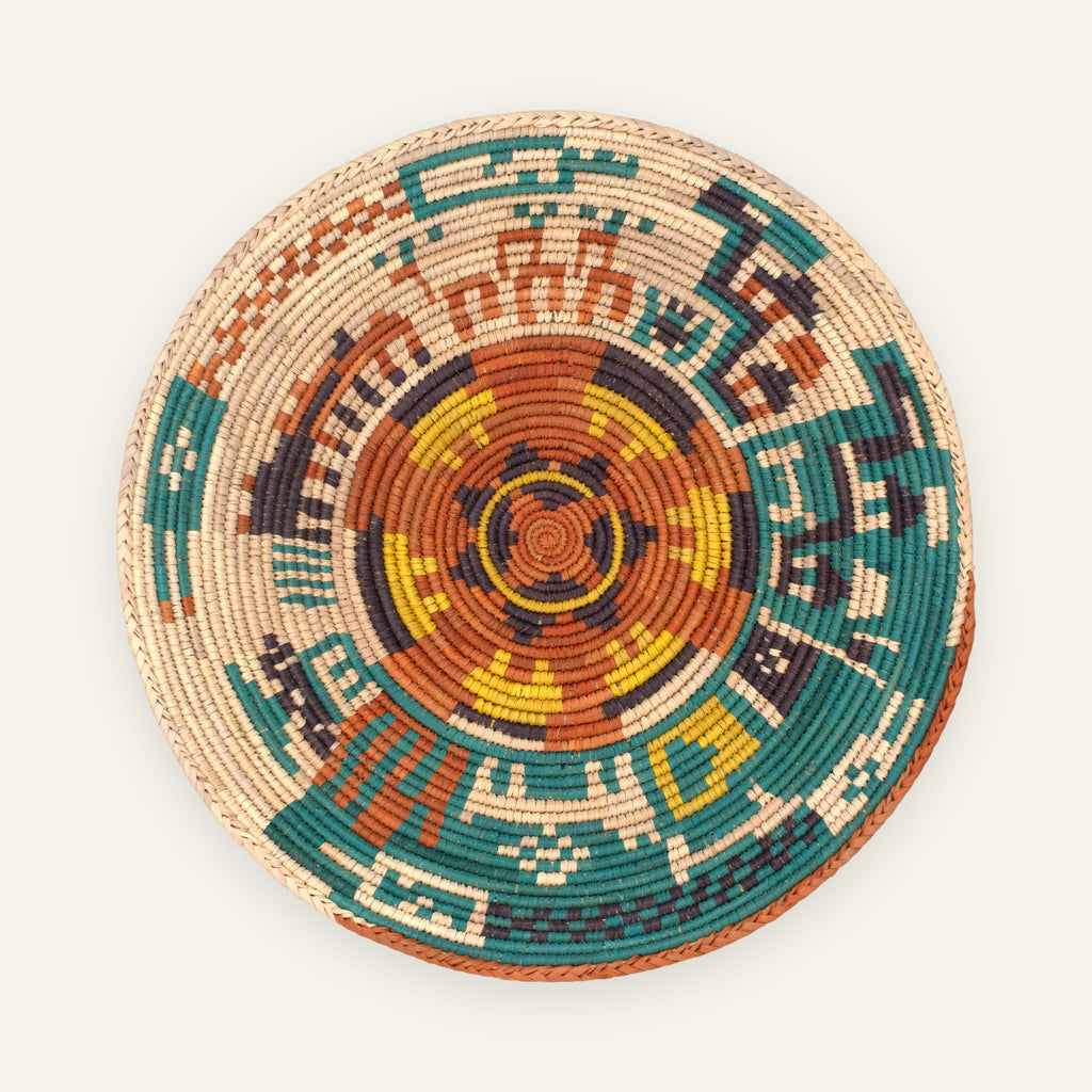 Jungle Lore Rustic handmade woven wicker wall basket with a terracotta, teal, yellow, purple, and natural beige geometric circular pattern.