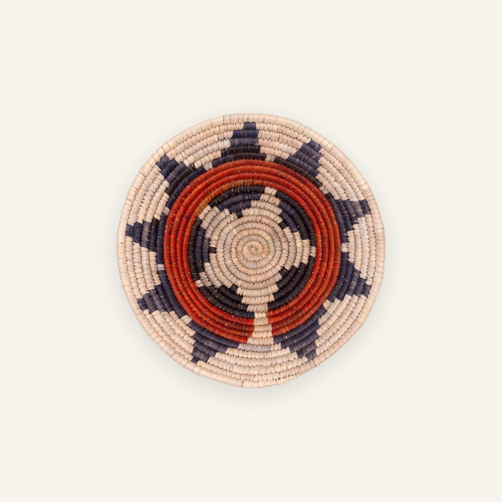 Little Bloom handmade woven wicker wall basket with concentric beige, red, and black geometric rings
