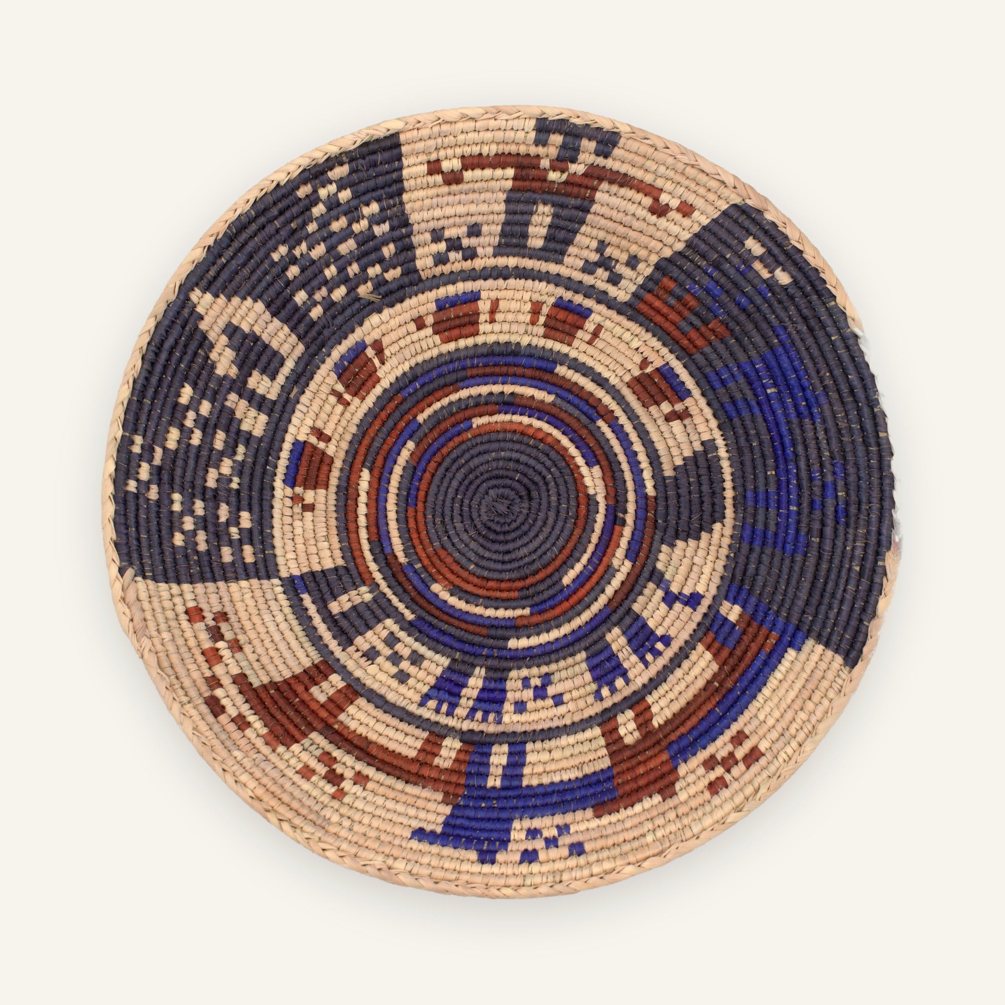 Majestic Turtle Midnight woven wicker wall basket with a dark spiral center, beige geometric bands, blue accents, and earthy red details.