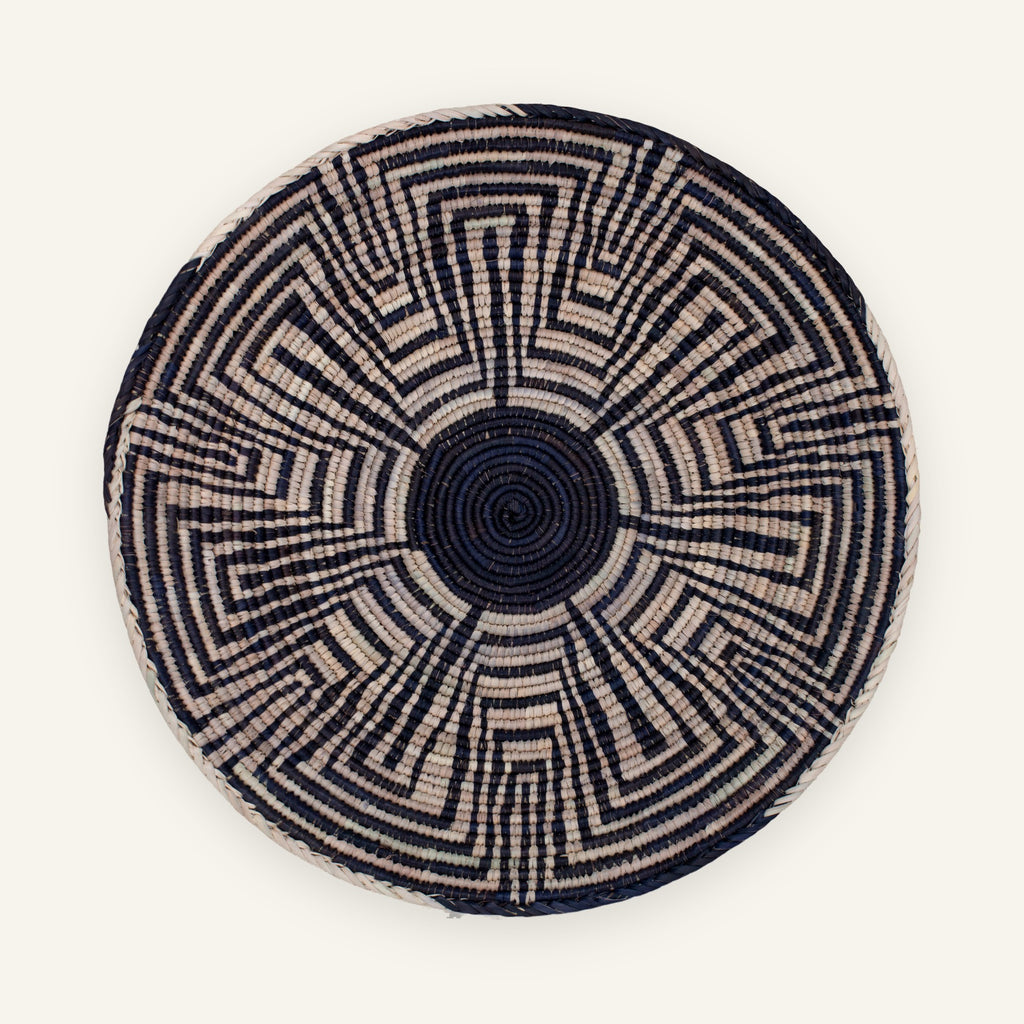 Maze woven wicker wall basket with a black center and geometric black and beige radial pattern.