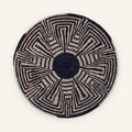 Maze woven wicker wall basket with a black center and geometric black and beige radial pattern.