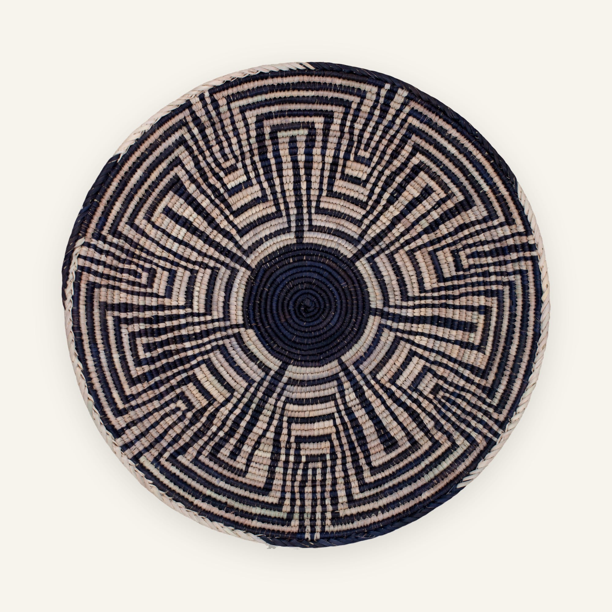 Maze woven wicker wall basket with a black center and geometric black and beige radial pattern.