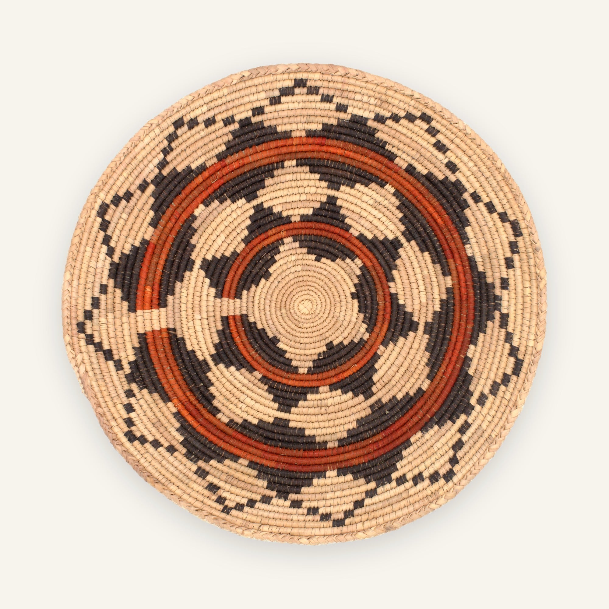 Mesa Rhythm handmade woven wicker wall basket with concentric geometric rings in beige, black, and earthy orange.