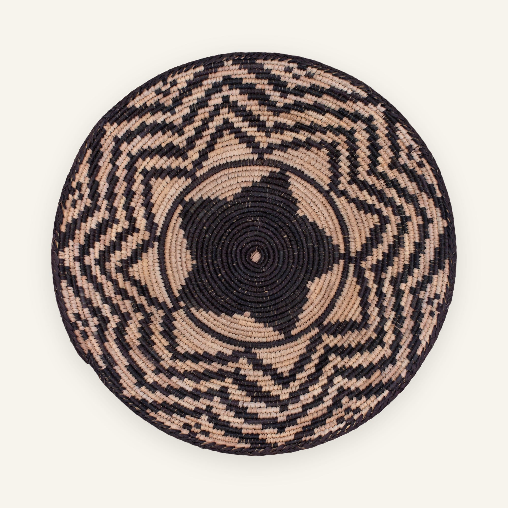 Nightfall woven wicker wall basket with a black center and irregular beige geometric bands.