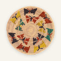 Spring woven wicker wall basket with a natural beige ground and circular geometric blocks in red, yellow, green, and charcoal.
