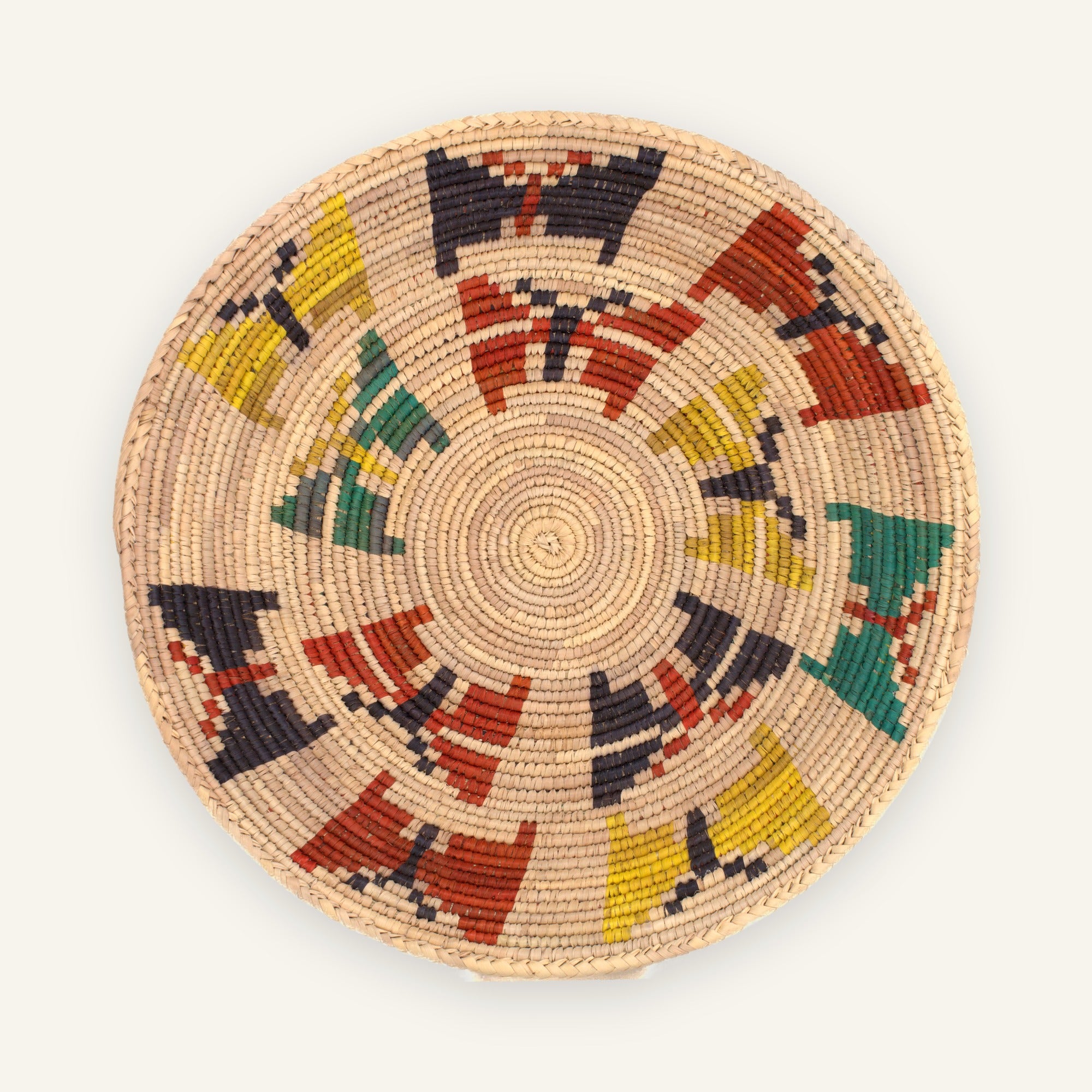 Spring woven wicker wall basket with a natural beige ground and circular geometric blocks in red, yellow, green, and charcoal.