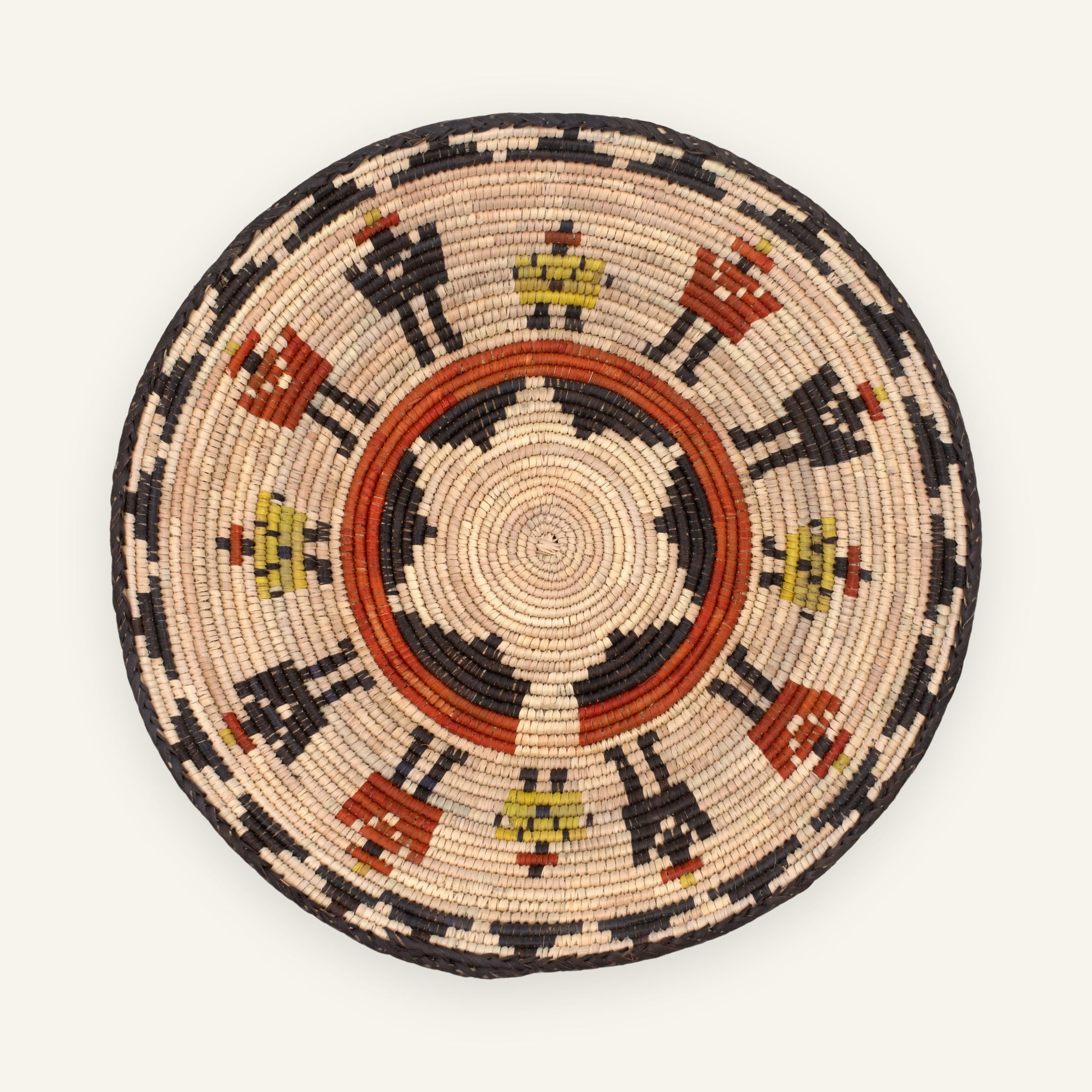 Squad woven wicker wall basket with concentric beige, black, orange, and yellow geometric patterning