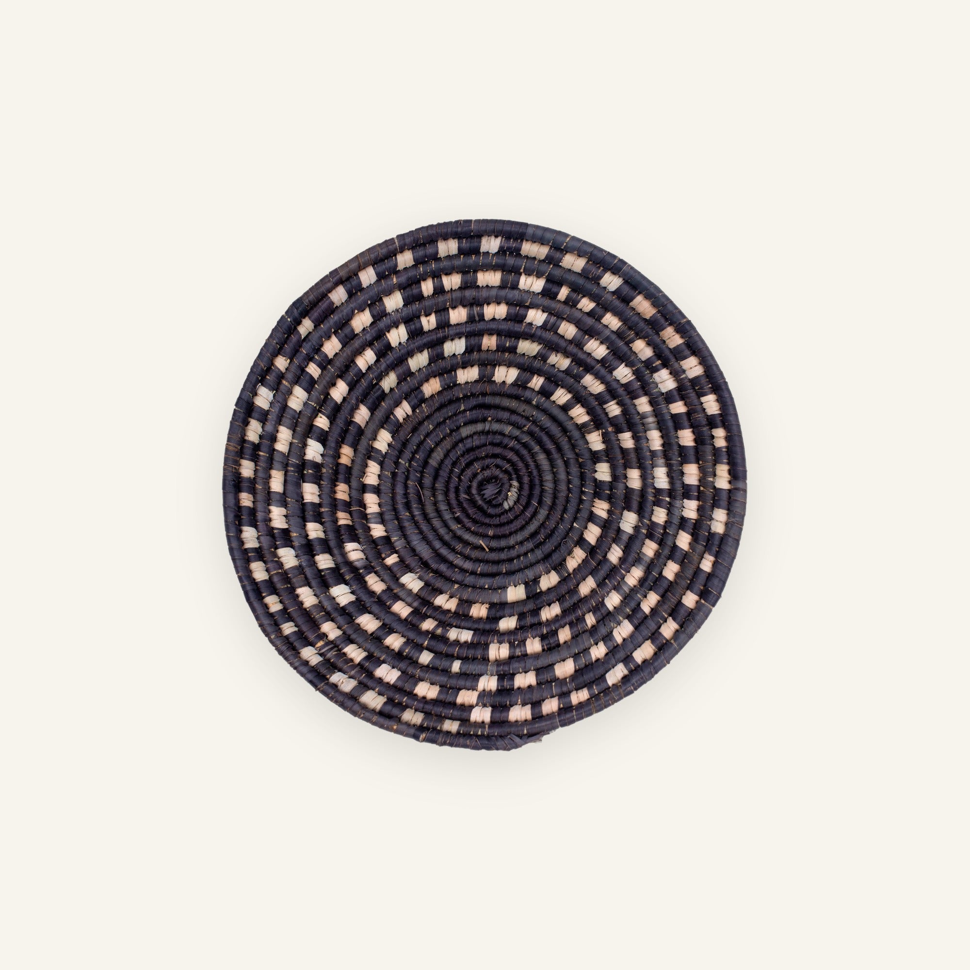 Stellar mini woven wicker wall basket with black concentric coils and beige dashed circular pattern.