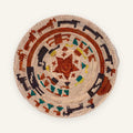 Stories Obsidian woven wicker wall basket with rust-red circular bands, dark arcs, teal details, and yellow accents on a natural beige ground.